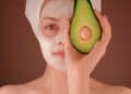 woman with white face mask holding green fruit